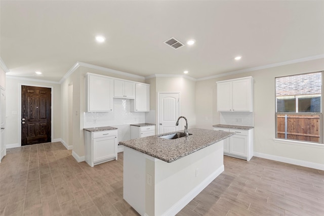 kitchen with a center island with sink, white cabinetry, and sink