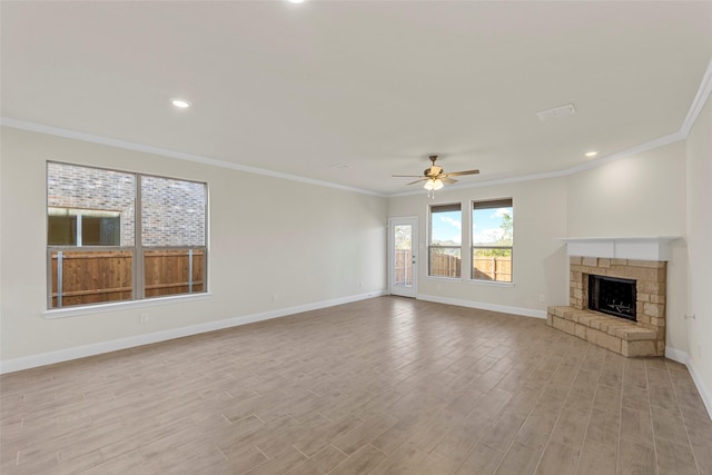 unfurnished living room with light wood-type flooring, a stone fireplace, ceiling fan, and ornamental molding