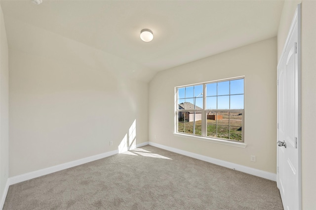 carpeted spare room featuring lofted ceiling