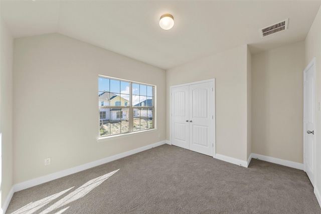 unfurnished bedroom with carpet flooring, vaulted ceiling, and a closet