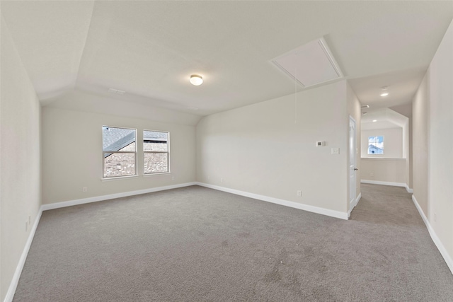 carpeted spare room featuring vaulted ceiling