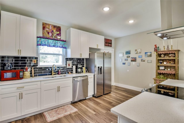 kitchen featuring light wood-type flooring, tasteful backsplash, stainless steel appliances, sink, and white cabinets