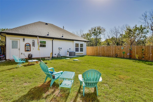 rear view of property with central AC unit and a yard