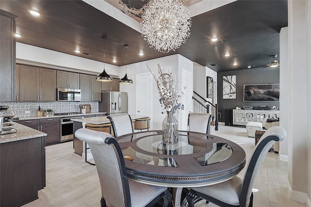 dining room featuring ceiling fan with notable chandelier and light hardwood / wood-style flooring