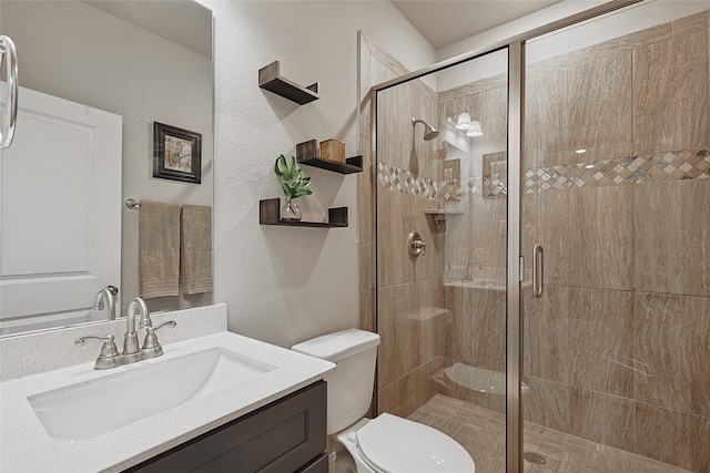 bathroom featuring toilet, a shower with door, and vanity