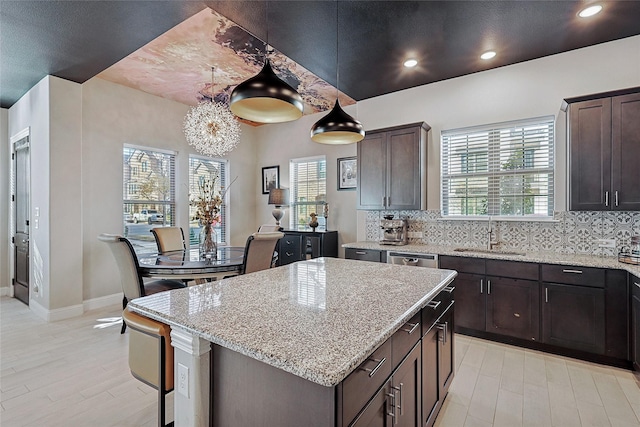 kitchen with sink, hanging light fixtures, a center island, and dark brown cabinetry