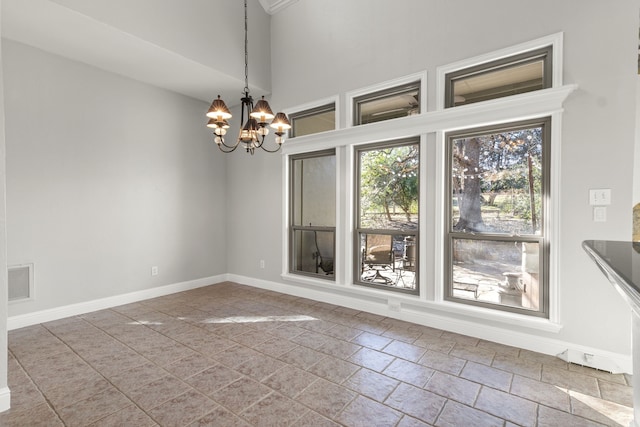 unfurnished dining area featuring a towering ceiling and a notable chandelier