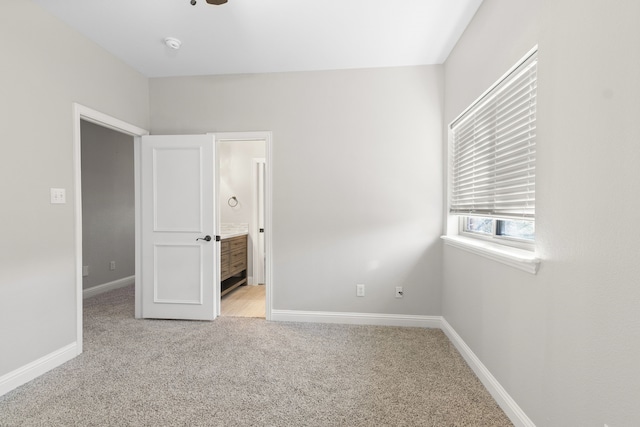 unfurnished bedroom featuring ensuite bathroom, ceiling fan, and light carpet