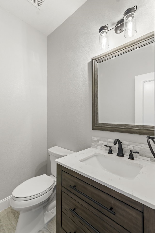 bathroom with backsplash, vanity, wood-type flooring, and toilet