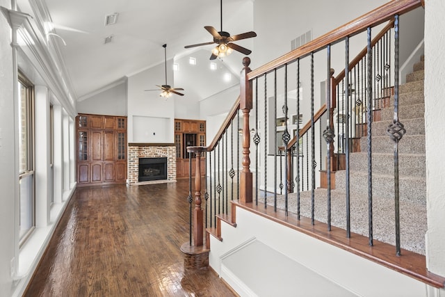 unfurnished living room featuring ceiling fan, dark hardwood / wood-style flooring, crown molding, and a brick fireplace