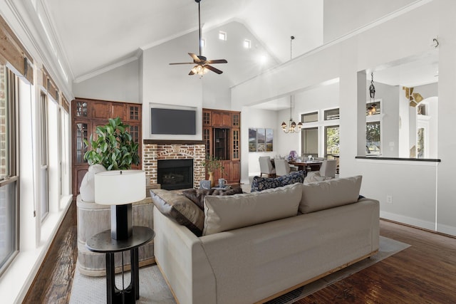 living room with a brick fireplace, dark hardwood / wood-style flooring, high vaulted ceiling, crown molding, and ceiling fan with notable chandelier