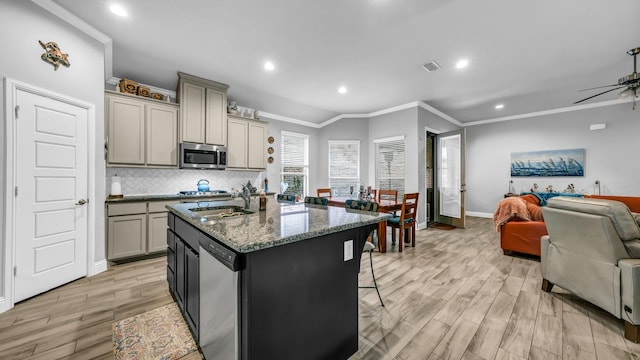 kitchen featuring gray cabinets, an island with sink, appliances with stainless steel finishes, and light hardwood / wood-style flooring