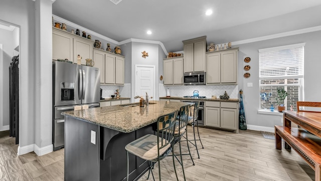 kitchen featuring gray cabinetry, a breakfast bar, sink, ornamental molding, and appliances with stainless steel finishes