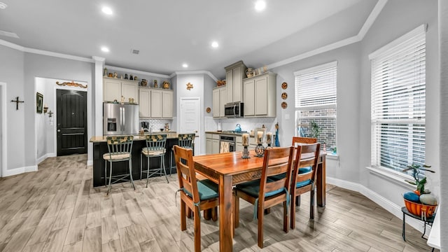 dining space with crown molding and light hardwood / wood-style flooring