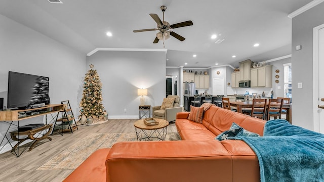 living room featuring lofted ceiling, light hardwood / wood-style flooring, ceiling fan, and ornamental molding