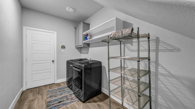 clothes washing area featuring cabinets, washer and dryer, hardwood / wood-style floors, and a textured ceiling