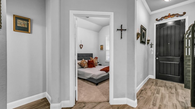 foyer entrance with crown molding, light hardwood / wood-style flooring, and lofted ceiling