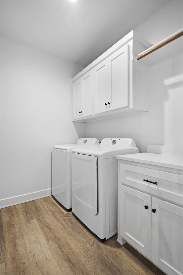 laundry room with separate washer and dryer, cabinets, and light wood-type flooring