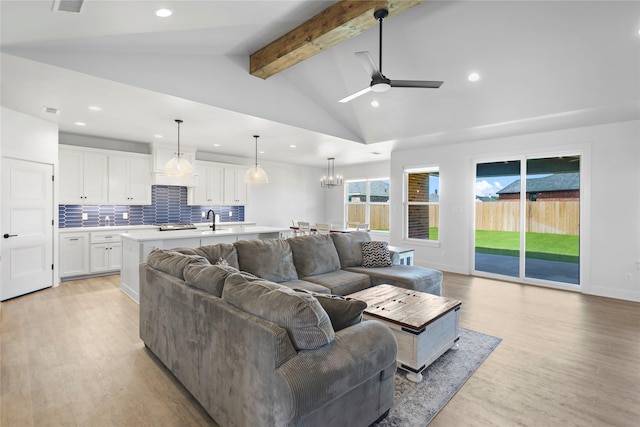 living room featuring ceiling fan with notable chandelier, sink, lofted ceiling with beams, and light hardwood / wood-style flooring