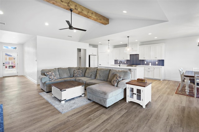 living room featuring vaulted ceiling with beams, ceiling fan, sink, and light hardwood / wood-style flooring