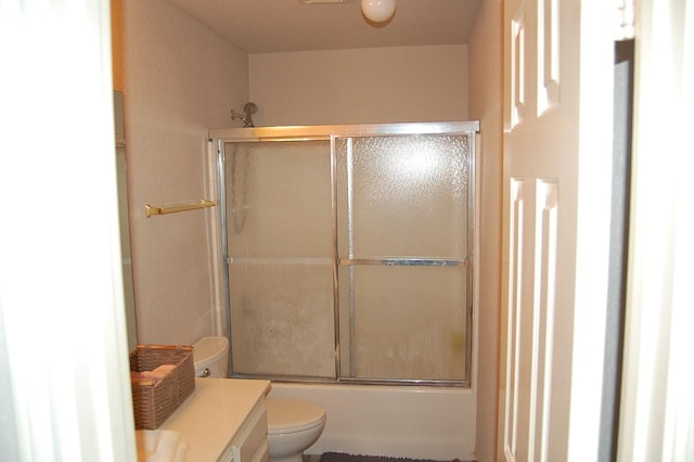 bathroom with toilet, enclosed tub / shower combo, and vanity