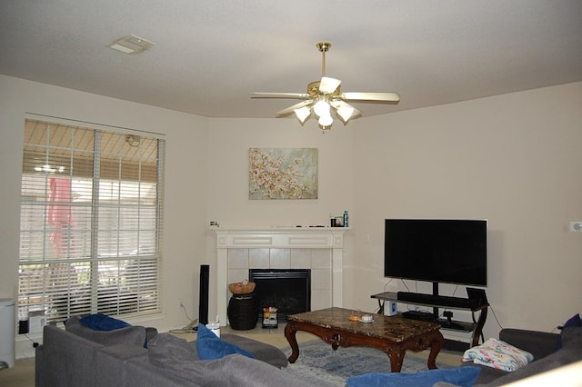 living room featuring visible vents, a tile fireplace, and a ceiling fan