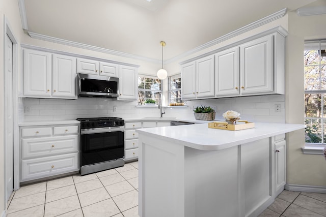 kitchen with a wealth of natural light, sink, hanging light fixtures, tasteful backsplash, and appliances with stainless steel finishes