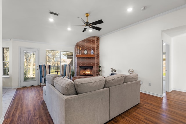 living room with a fireplace, ceiling fan, dark hardwood / wood-style flooring, and vaulted ceiling