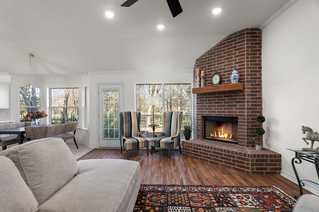 living room featuring lofted ceiling, ceiling fan, ornamental molding, a fireplace, and wood-type flooring