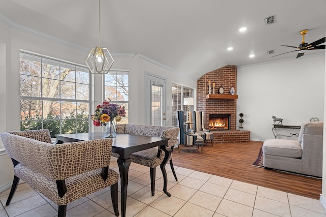 dining space with ceiling fan, light hardwood / wood-style flooring, lofted ceiling, a fireplace, and ornamental molding