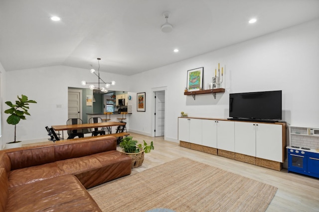 living room with vaulted ceiling, a notable chandelier, and light wood-type flooring