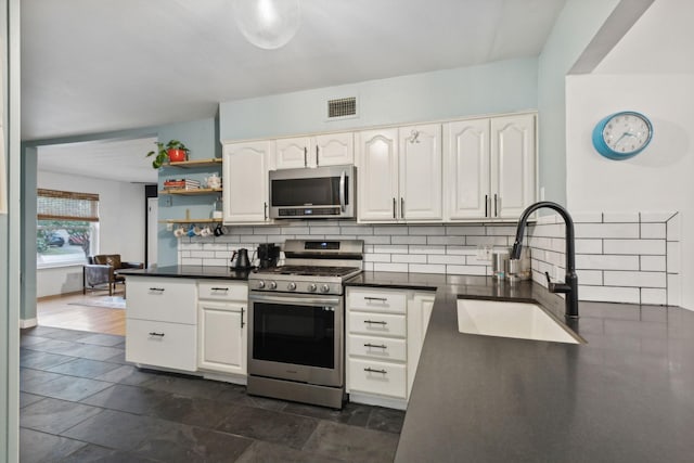 kitchen featuring tasteful backsplash, white cabinetry, sink, and stainless steel appliances