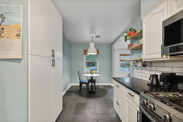 kitchen featuring white cabinets, decorative backsplash, hanging light fixtures, and appliances with stainless steel finishes