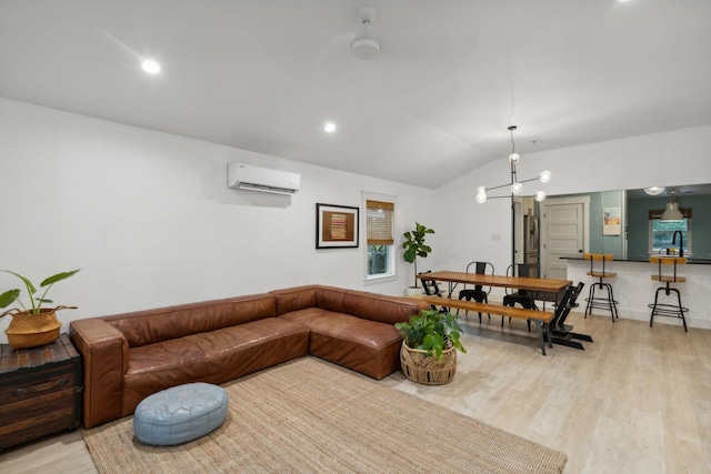 living room featuring light wood-type flooring, a wall unit AC, lofted ceiling, and a notable chandelier