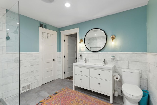 bathroom with vanity, tile walls, and toilet