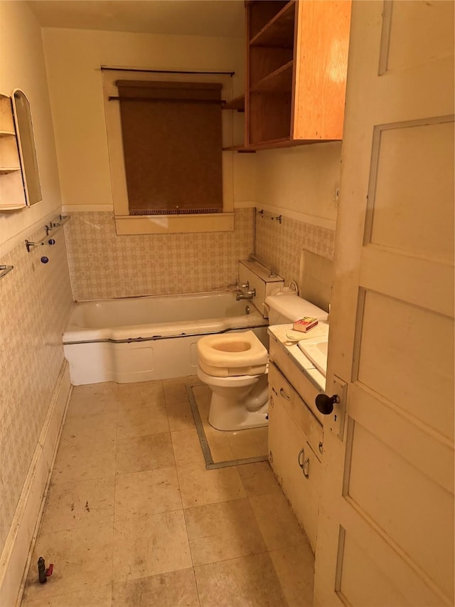 bathroom with a tub, vanity, tile walls, and toilet