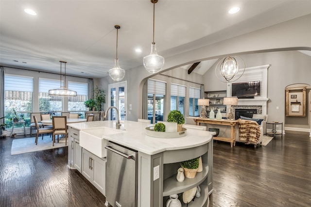 kitchen with sink, a kitchen island with sink, decorative light fixtures, vaulted ceiling, and stainless steel dishwasher