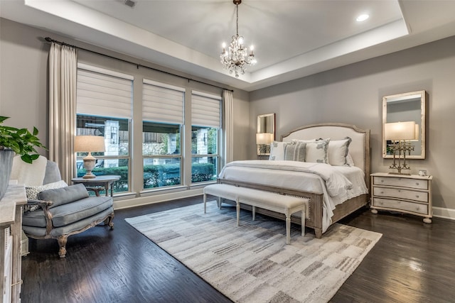 bedroom featuring an inviting chandelier, a tray ceiling, and dark hardwood / wood-style flooring