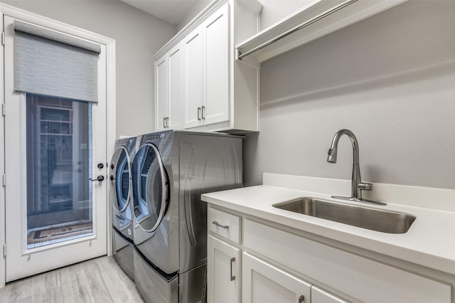 washroom featuring cabinets, independent washer and dryer, light hardwood / wood-style floors, and sink