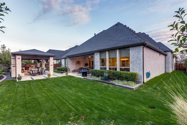 rear view of property featuring a gazebo, a yard, and a patio