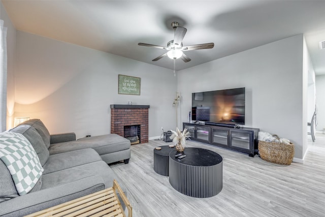 living room with ceiling fan, a fireplace, and light hardwood / wood-style floors