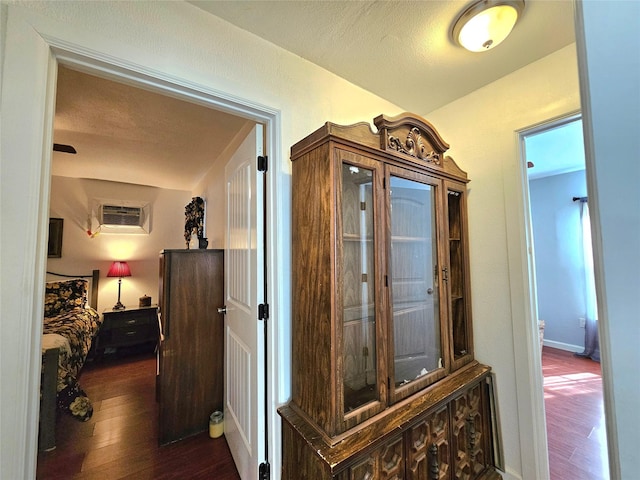 corridor with a wall mounted air conditioner, a textured ceiling, and dark hardwood / wood-style flooring