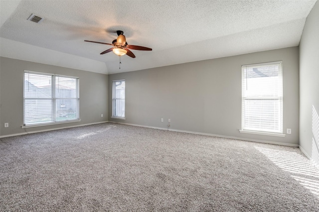 carpeted empty room featuring plenty of natural light, ceiling fan, and a textured ceiling