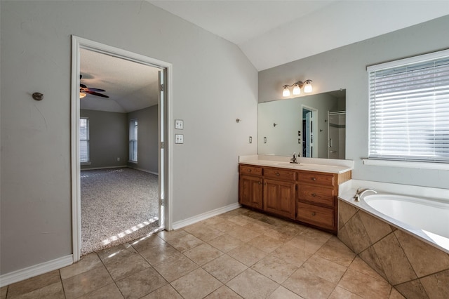 bathroom with vanity, vaulted ceiling, tile patterned flooring, ceiling fan, and tiled tub