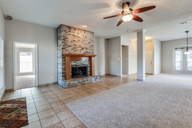 unfurnished living room featuring a textured ceiling, a brick fireplace, and plenty of natural light