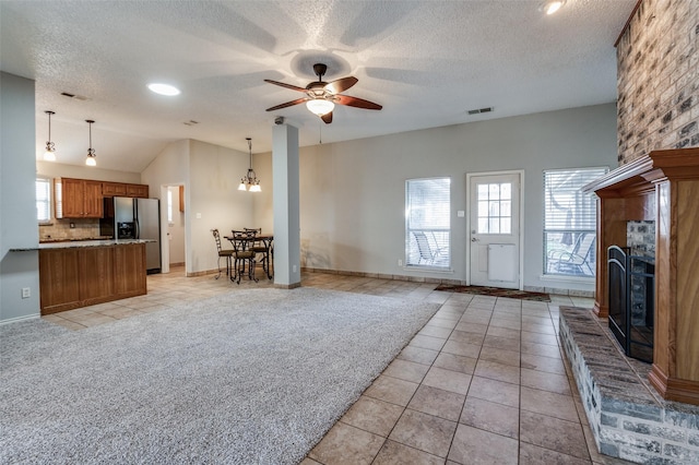 unfurnished living room featuring ceiling fan with notable chandelier, light tile patterned floors, a textured ceiling, and lofted ceiling