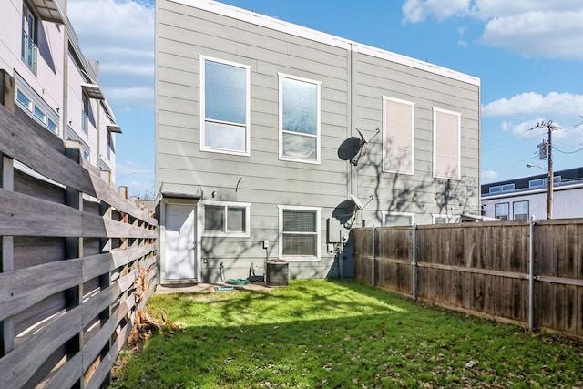 rear view of house with cooling unit and a lawn