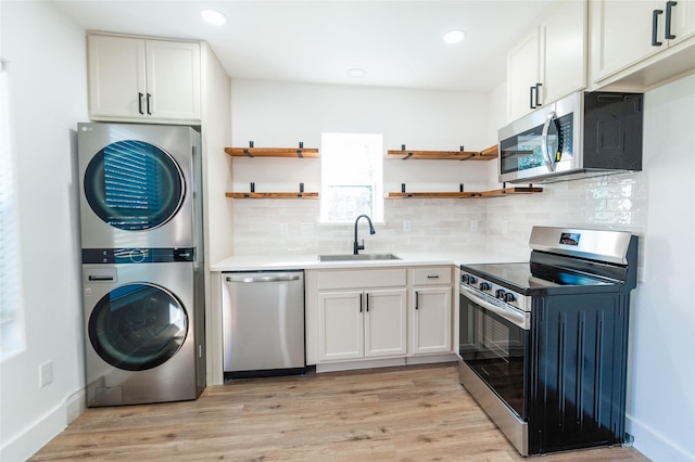 kitchen with white cabinets, sink, stacked washer / dryer, and appliances with stainless steel finishes