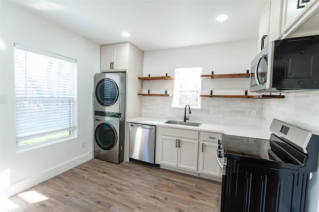 kitchen featuring white cabinetry, sink, stacked washer and clothes dryer, and appliances with stainless steel finishes