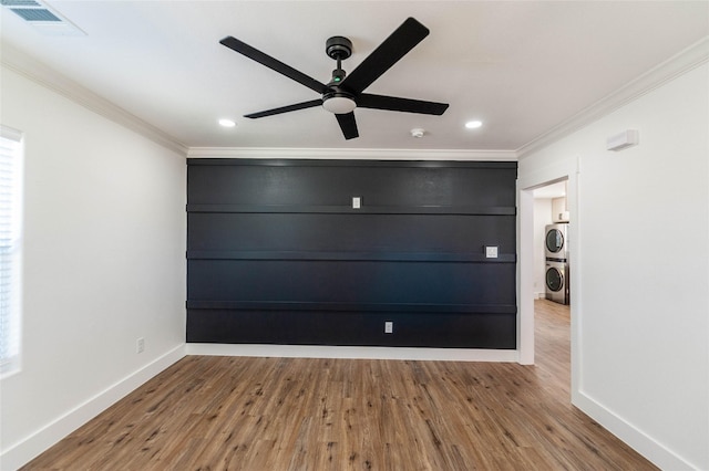 interior space with crown molding, light hardwood / wood-style flooring, ceiling fan, and stacked washer / drying machine